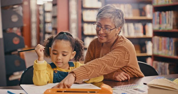 Grandmother and granddaughter reading together in a library